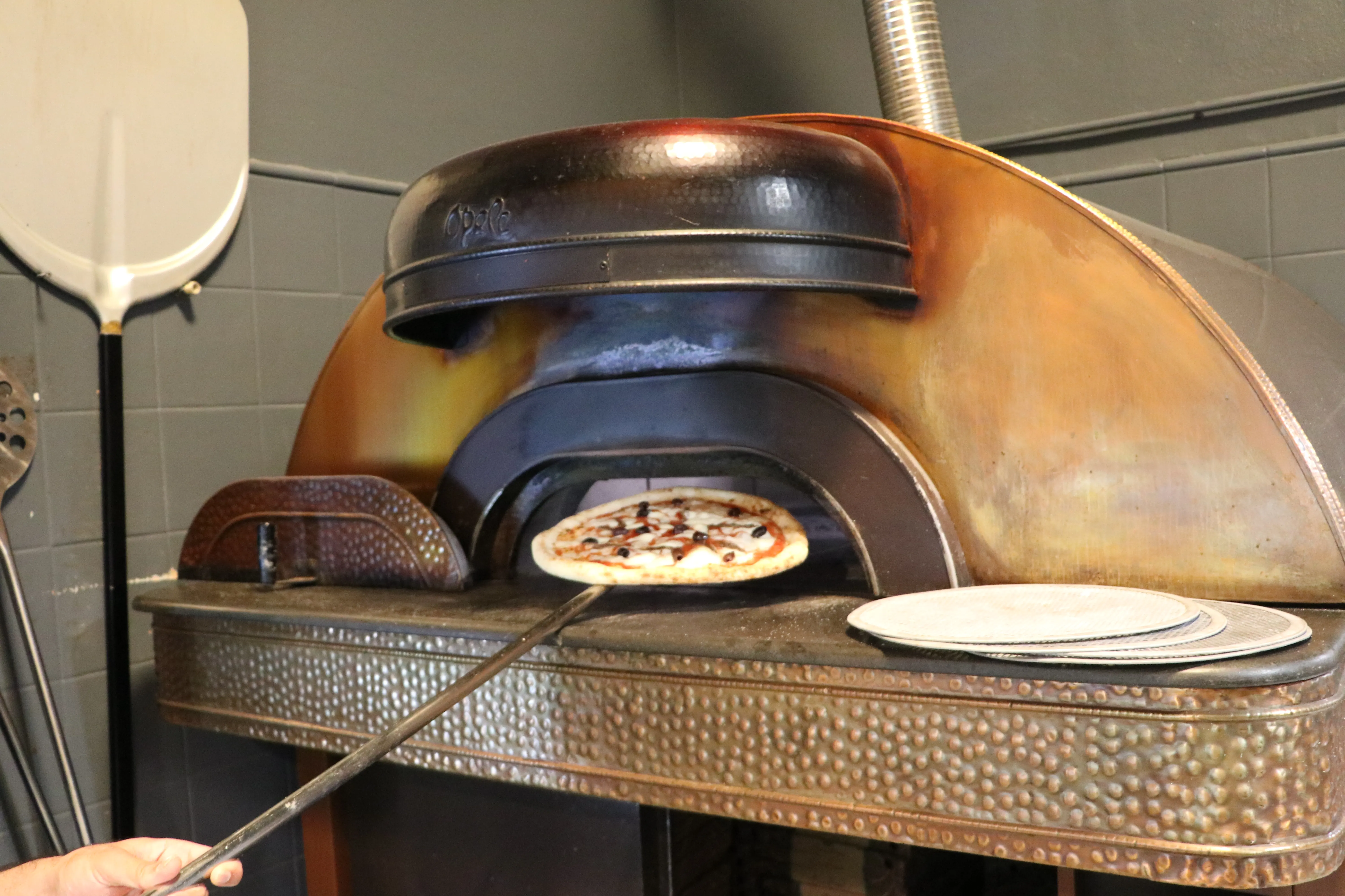 Una pizza cotta viene estratta dal forno con la pala