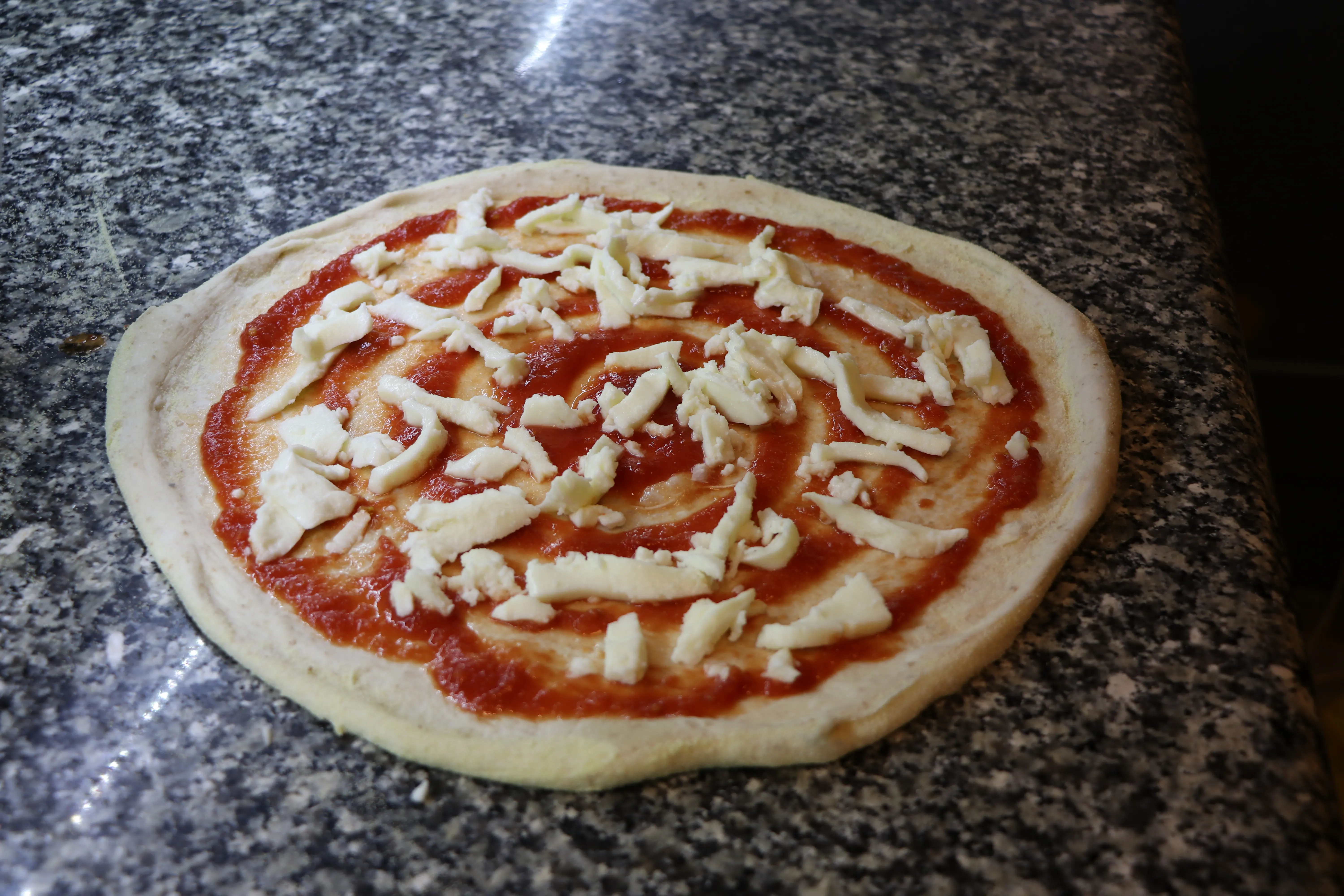 Una pizza con salsa e mozzarella pronta per la cottura