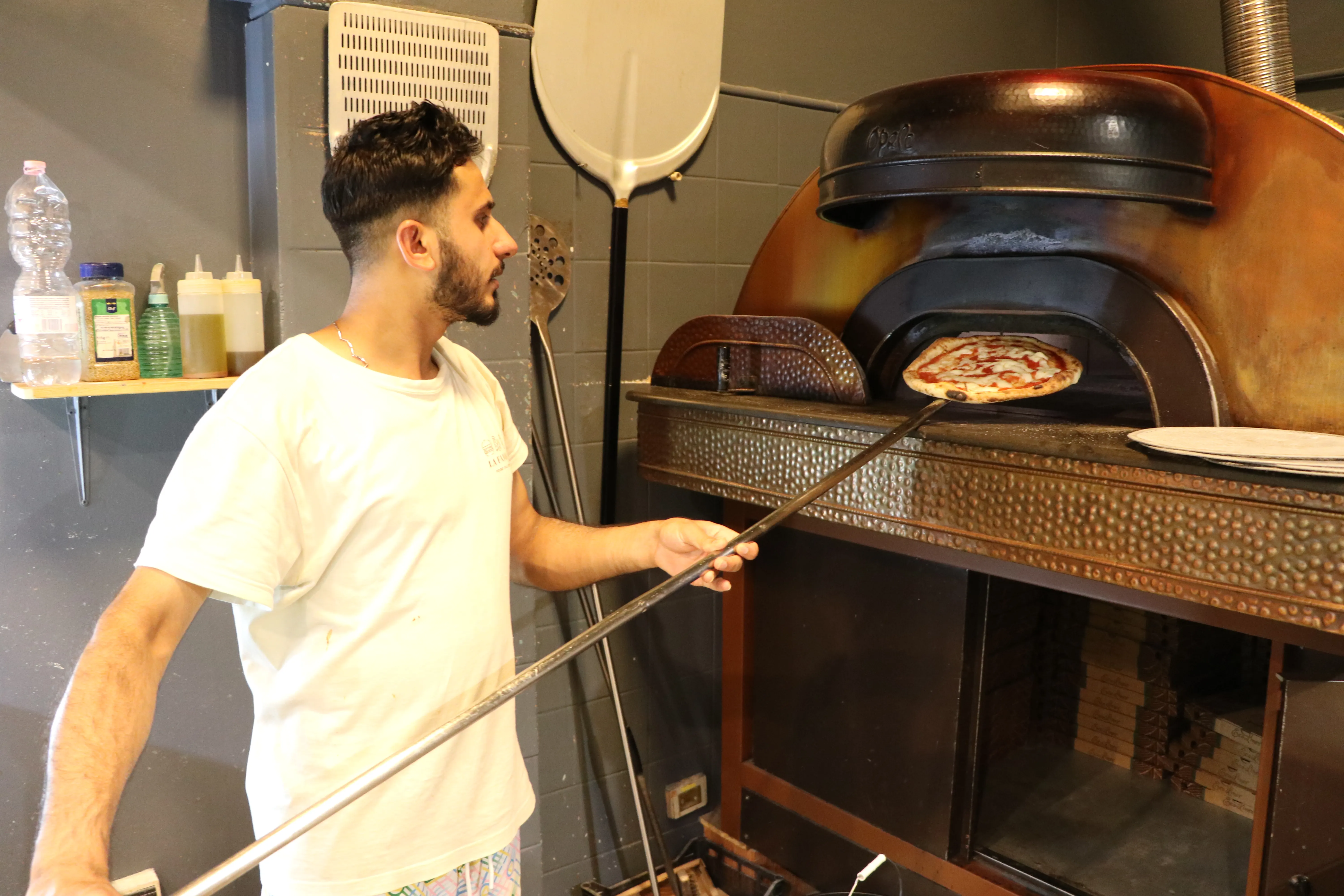 Il pizzaiolo La Favola segue la cottura davanti al forno