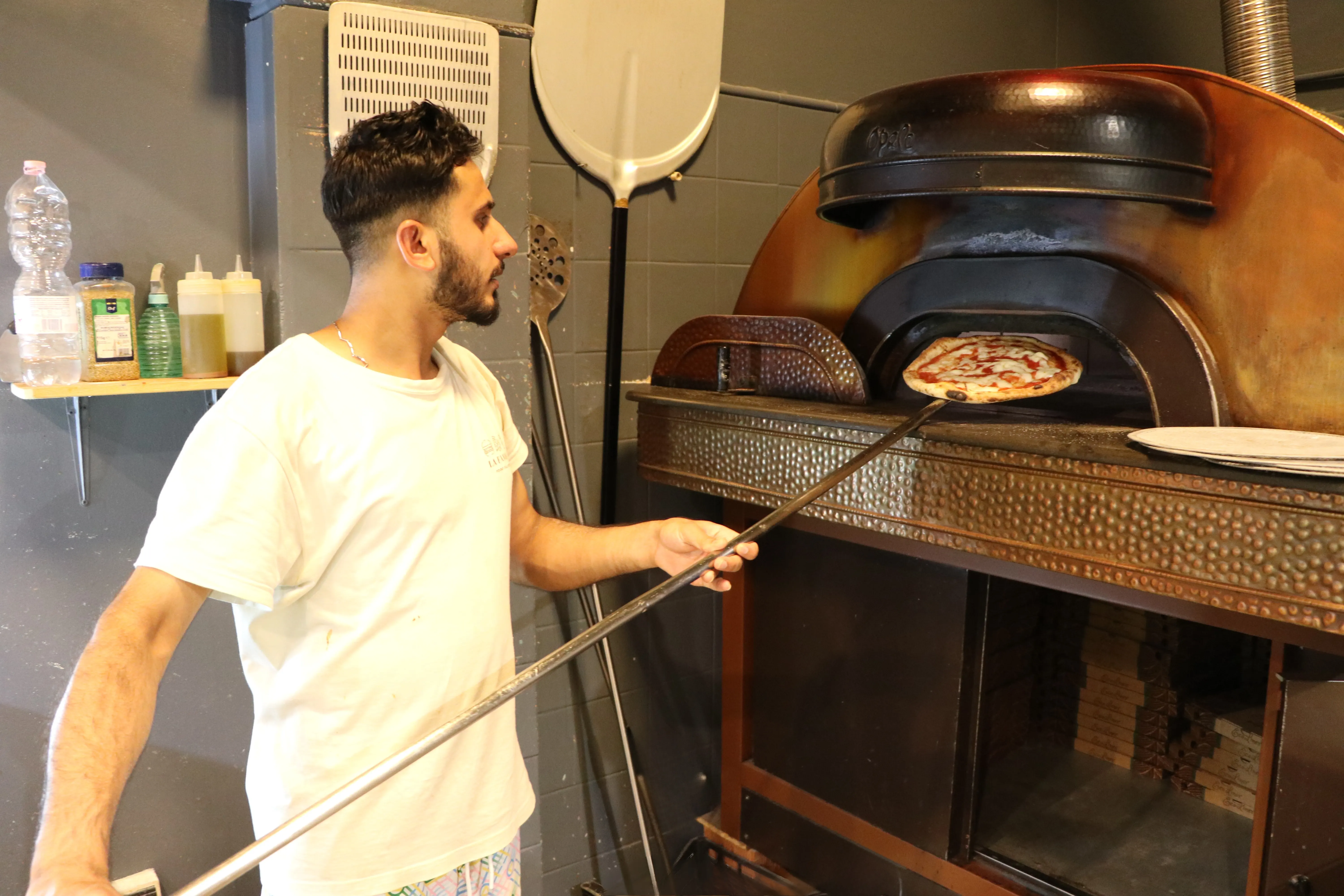 Il pizzaiolo La Favola controlla una pizza nel forno con la pala