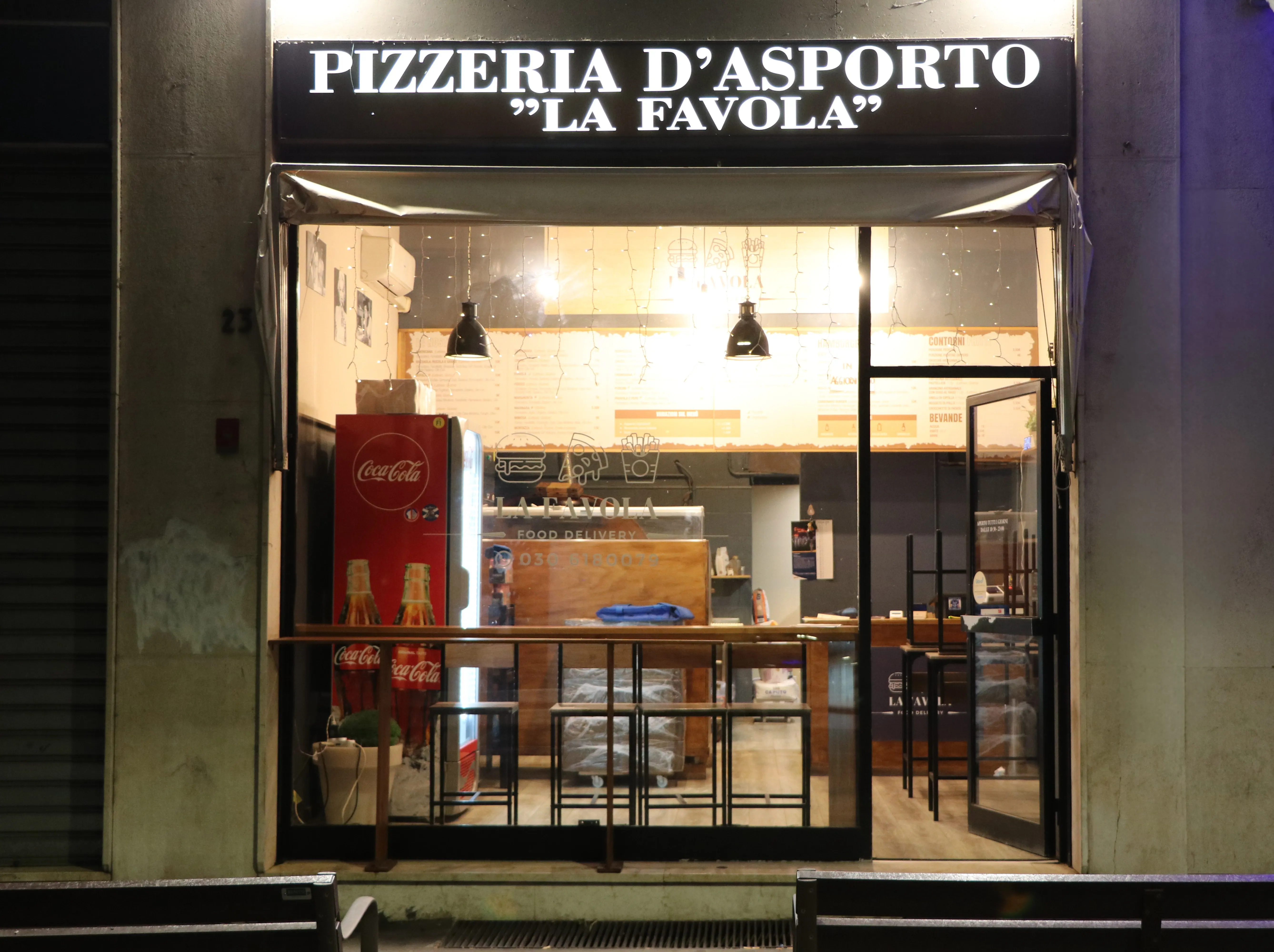 Ingresso notturno della pizzeria La Favola con l’insegna illuminata